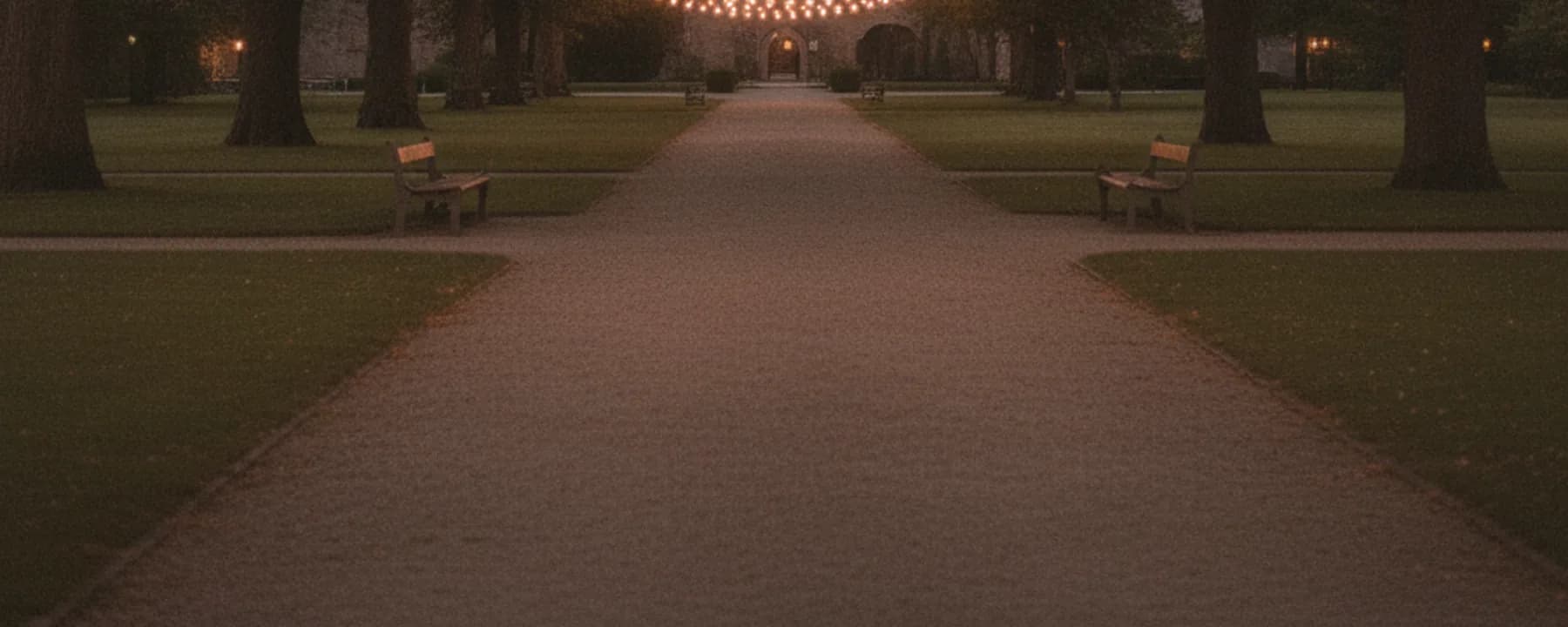 Schlosspark bei Dämmerung mit Lichterketten zwischen den Bäumen